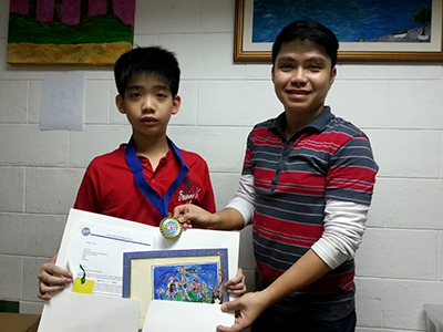 Jethro stands proudly with his Teacher displaying his prizes.