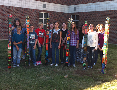 Carl Junction Junior High students pose with “peace poles” they installed Tuesday in front of the school. The project began last September and was part of an international peace pole mission that represents unity and friendship